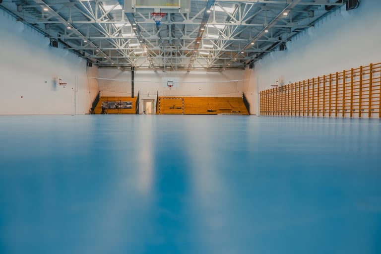 Wide shot of an empty sports hall with blue epoxy flooring and bleachers