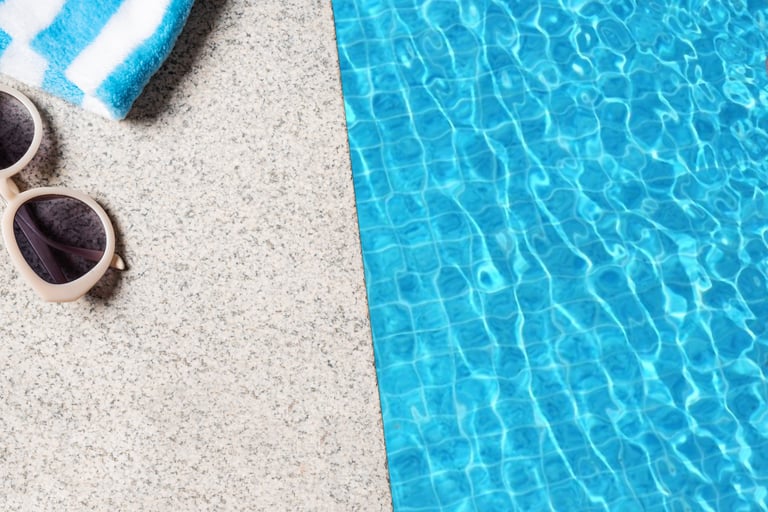 Edge of pool with beach towel and sunglasses and blue pool water texture