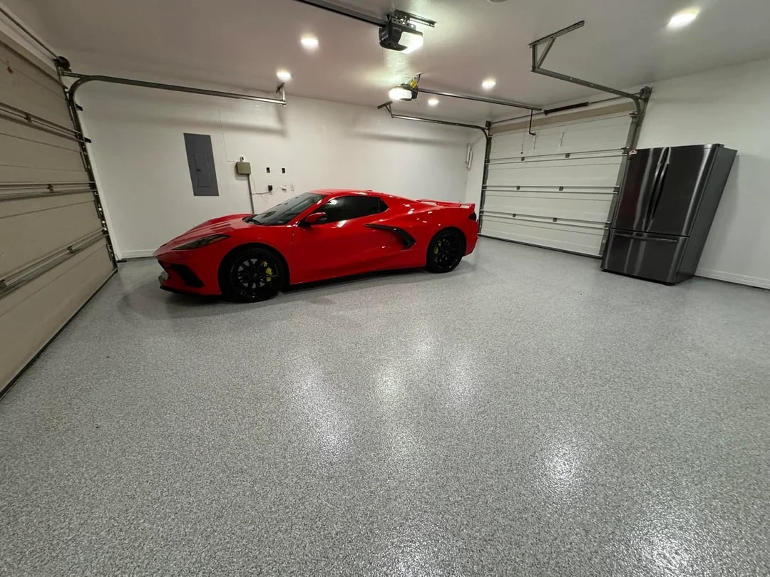 Red sports car parked in a clean garage with polished concrete floor and white walls