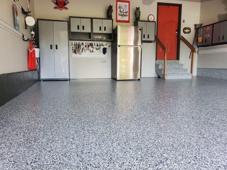 Clean epoxy-coated garage floor with organized wall storage refrigerator toolboxes and red door in background