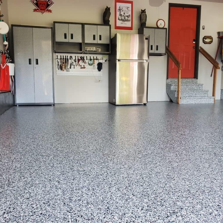 Organized garage interior with epoxy flooring wall-mounted storage refrigerator and red door